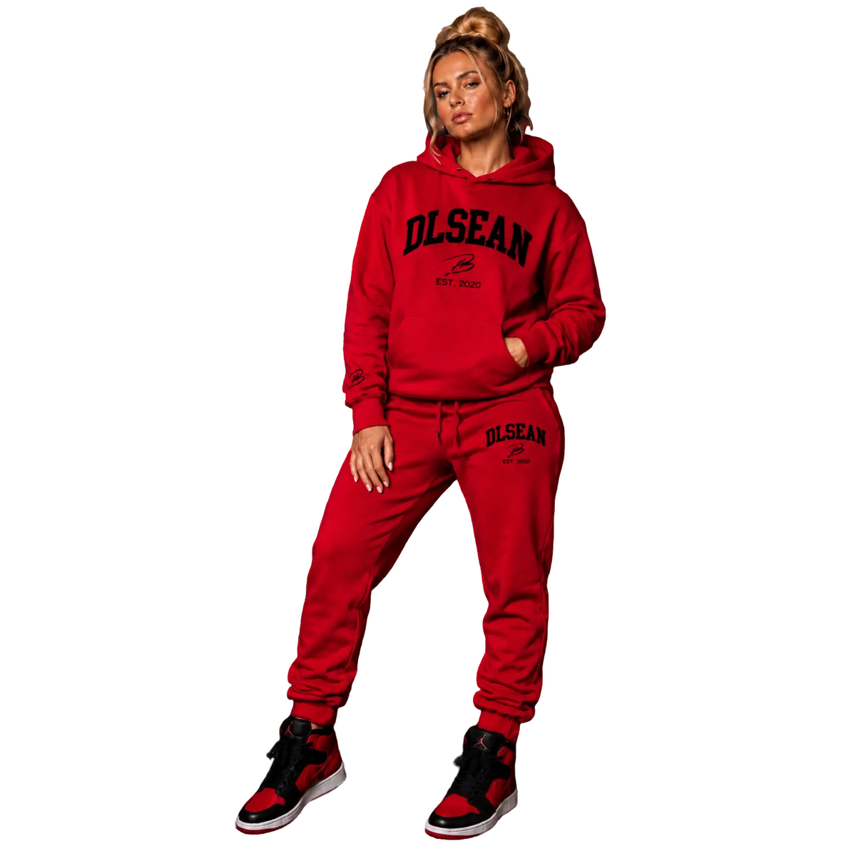 A woman modeling a matching red hoodie and sweatpants set with black 'OLSEAN EST. 2020' text printed on the front and thigh, paired with red and black sneakers, against a solid white background.